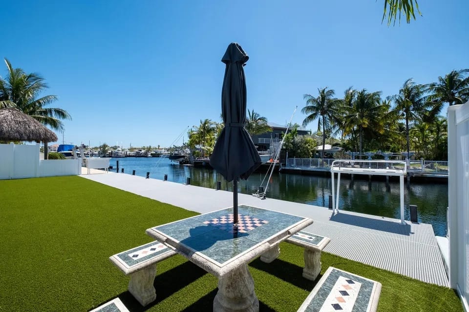 Backyard with outdoor game table, umbrella, and waterfront views